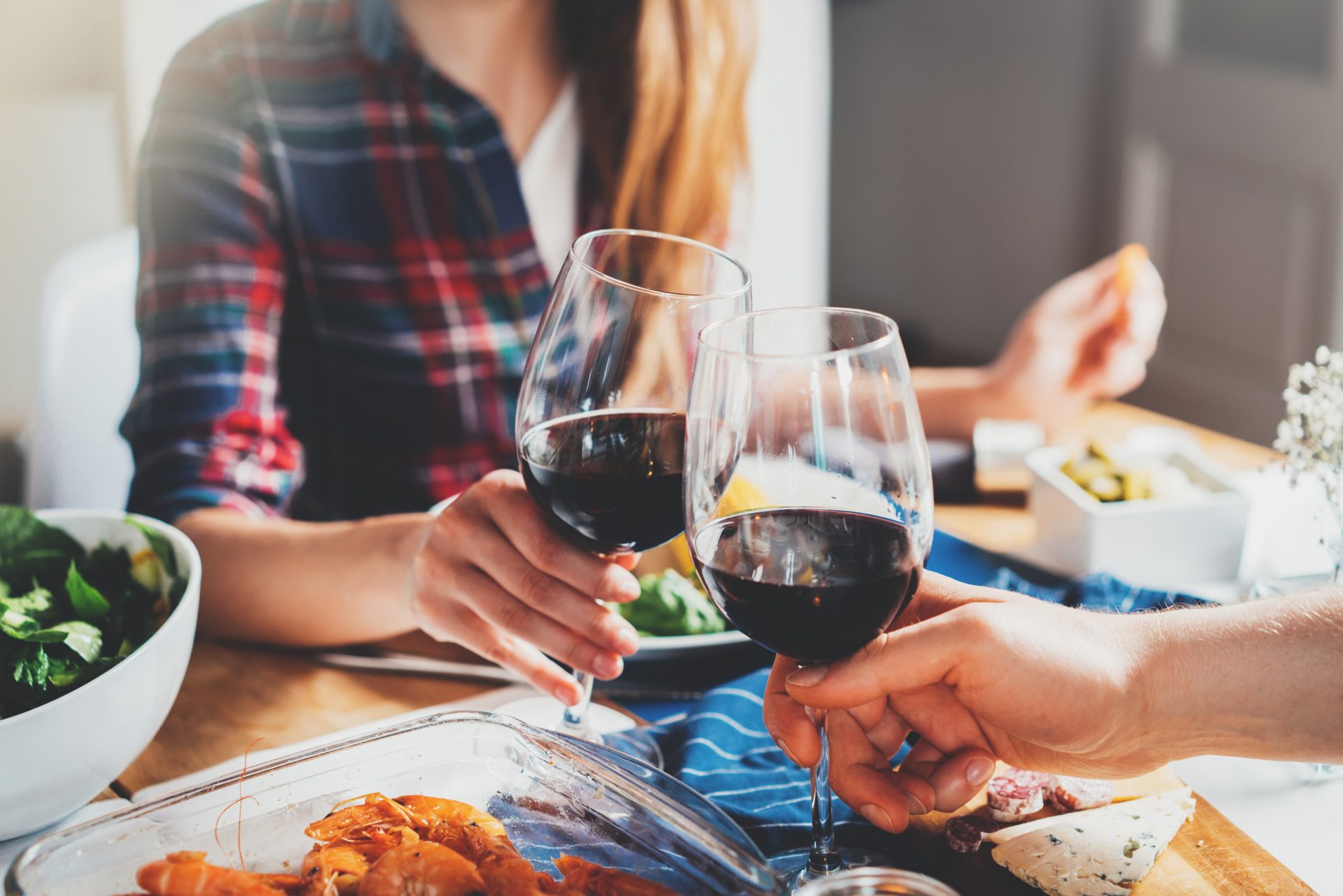 Couple cheers wine glasses filled with red liquid