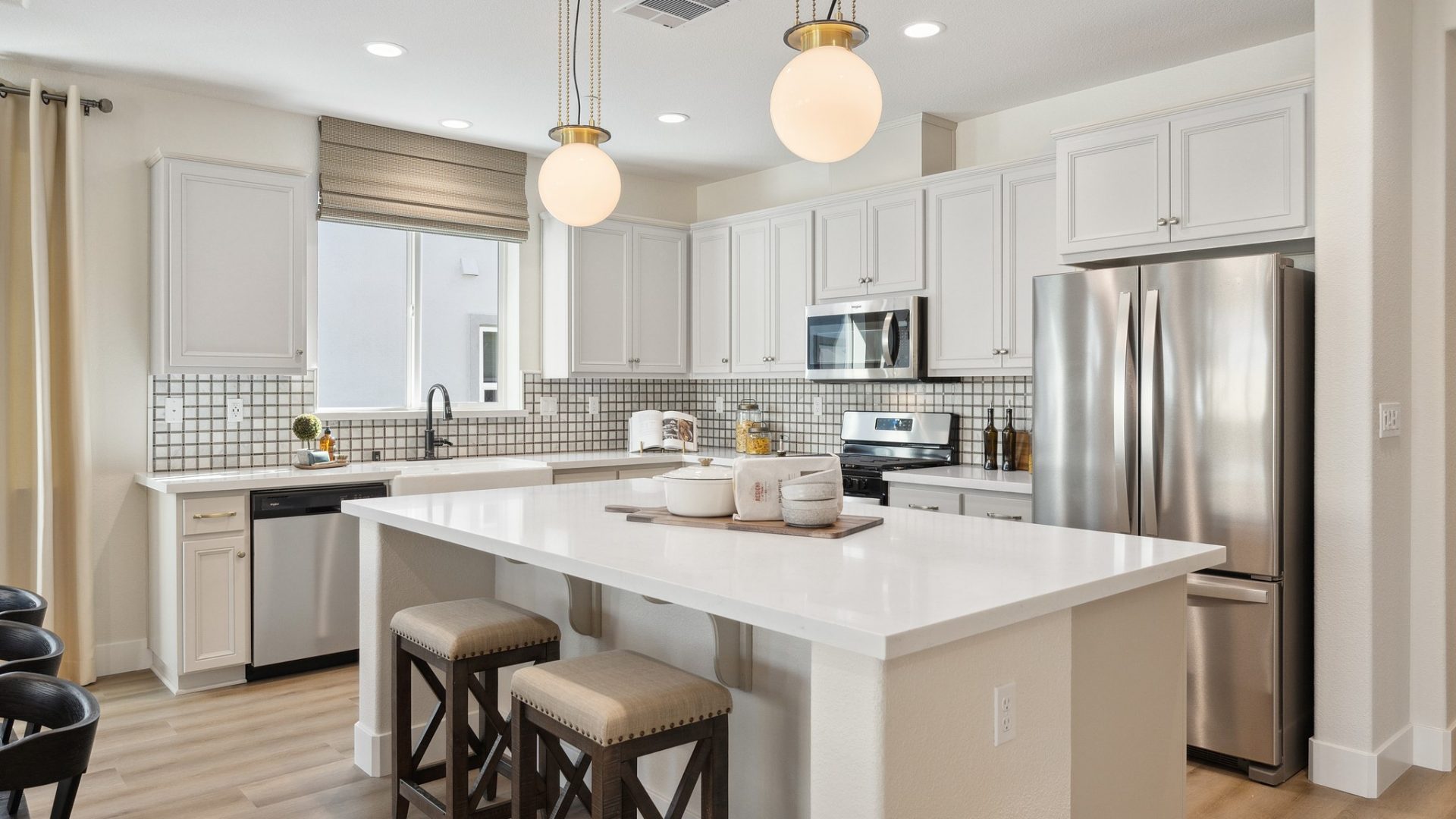 Designer kitchen with hardwood floors, stainless steel appliances, white beech wood cabinetry, white quartz countertops, 2 large pendants over kitchen island, and 9 foot ceilings with canned lights.