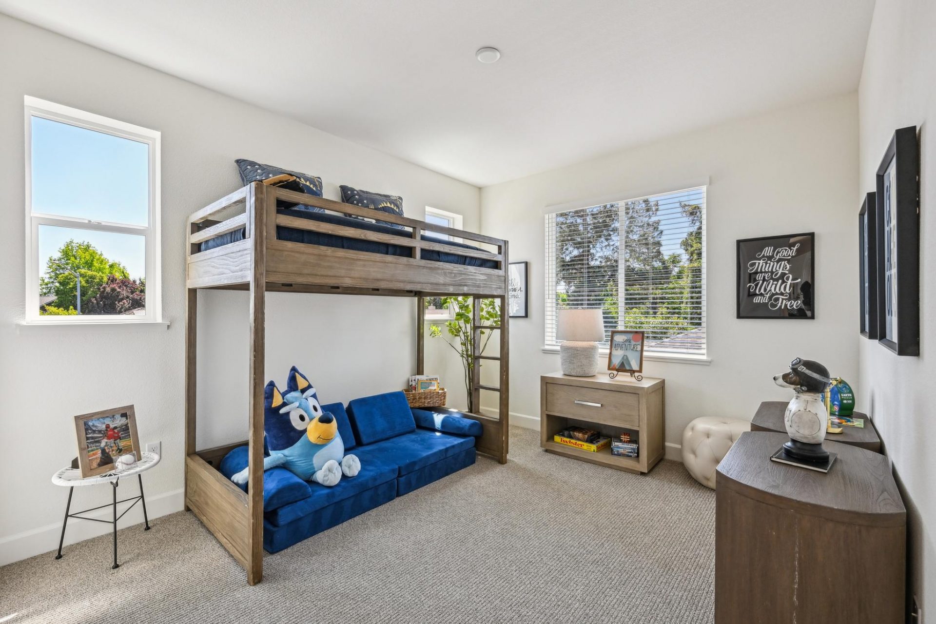 Carpeted bedroom with dark oak bunkbeds framed by 2 large windows, an additional third large window allowing tons of natural light, 9 foot ceilings with canned lighting.