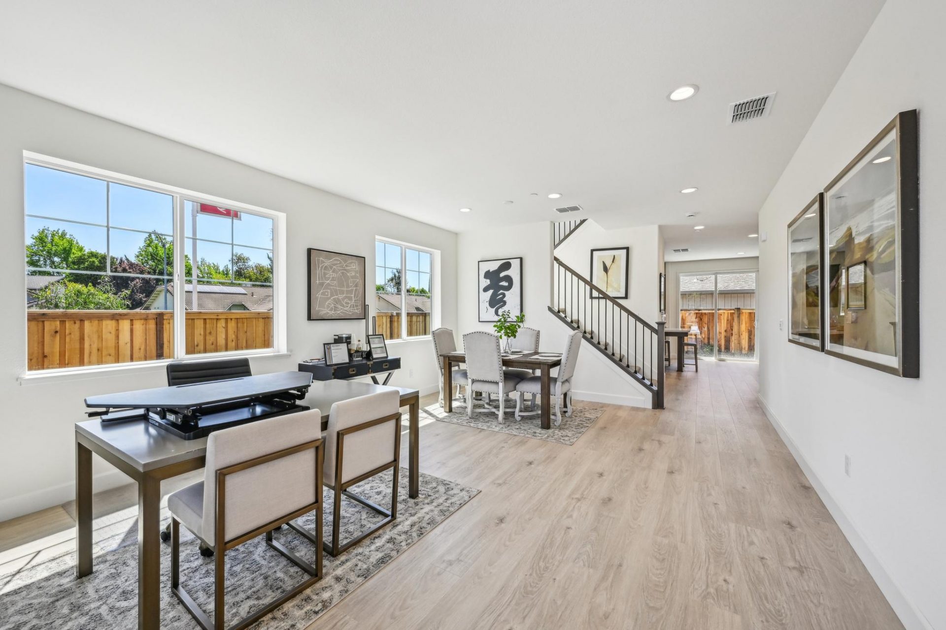 Open concept dinning room with staircase in the background, hardwood floors, 4 large windows with tons of natural light, 9 foot ceilings with canned lighting.