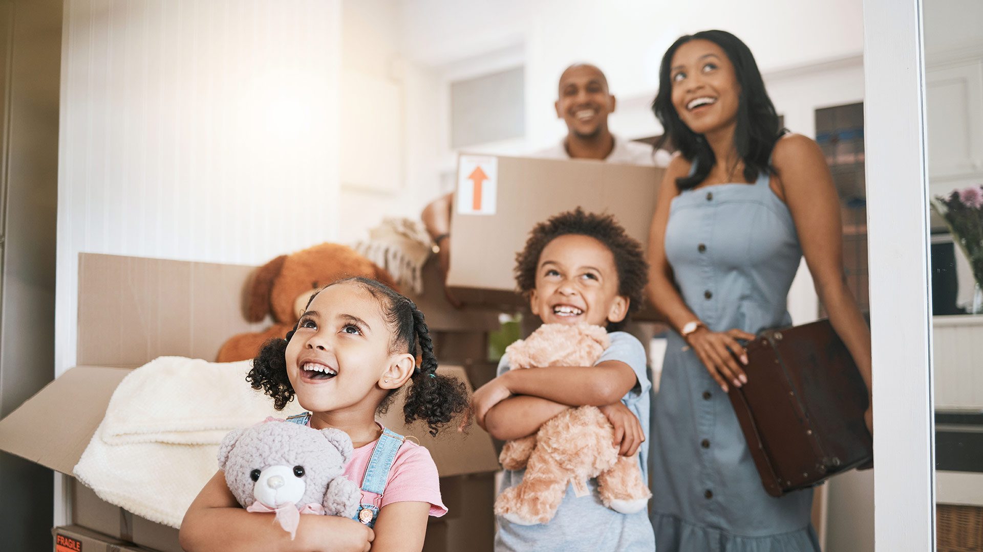 Family of four moving into new home with smiles and moving boxes