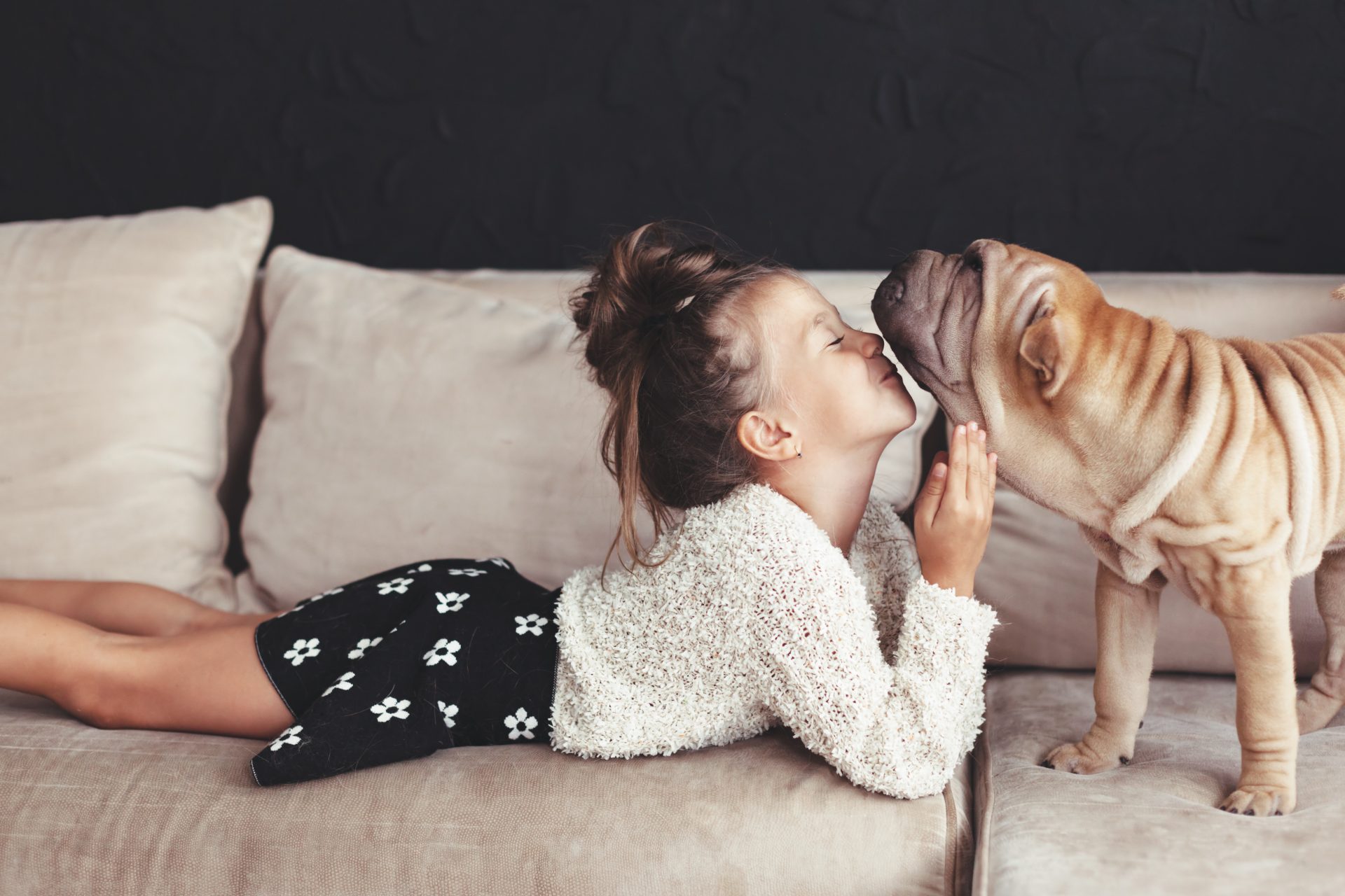 Little girl kissing shar pei dog