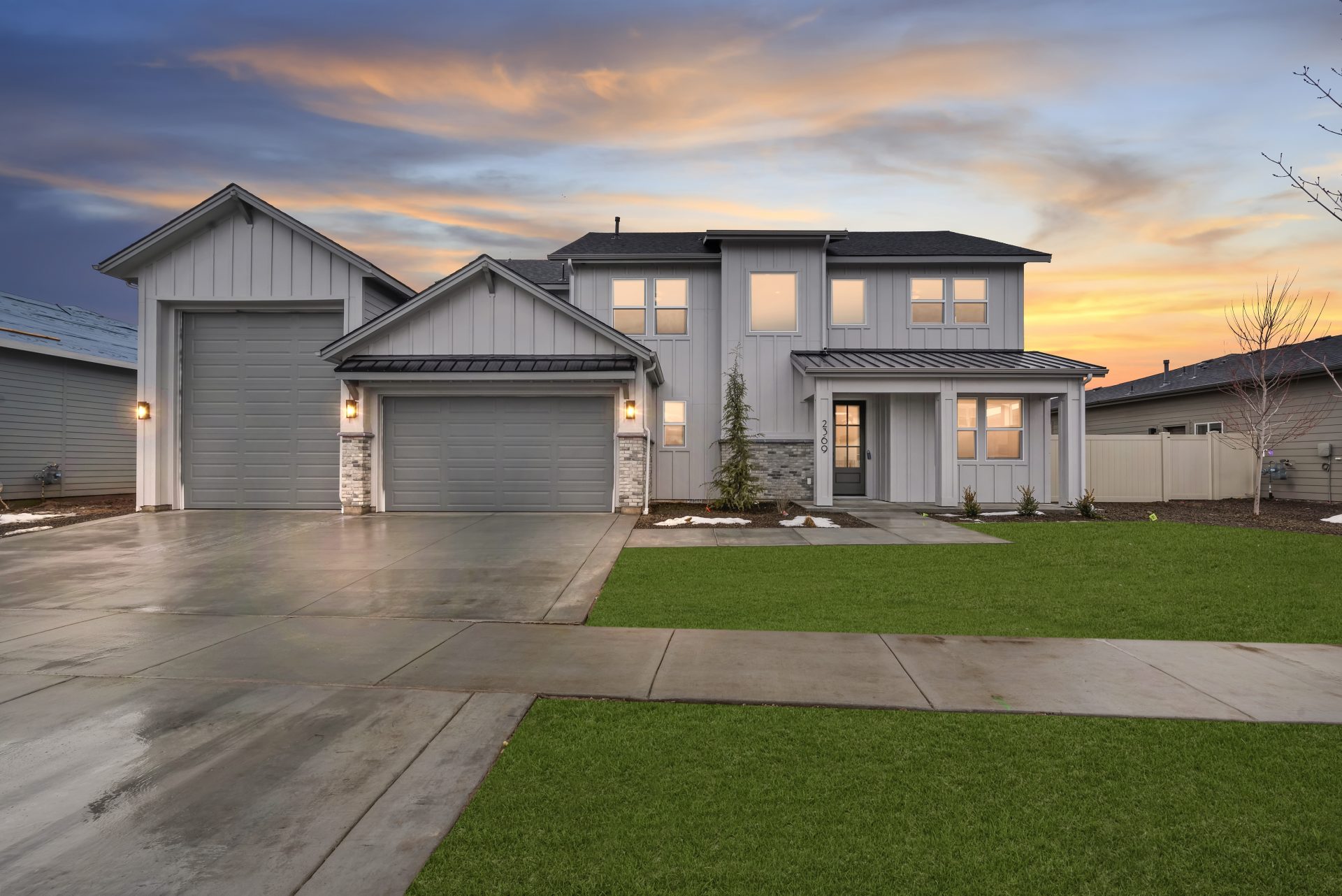 Exterior elevation of large craftsman style home with 2 car garage and additional attached RV garage, with covered patio front entrance and grass landscaping, painted in grey tones.