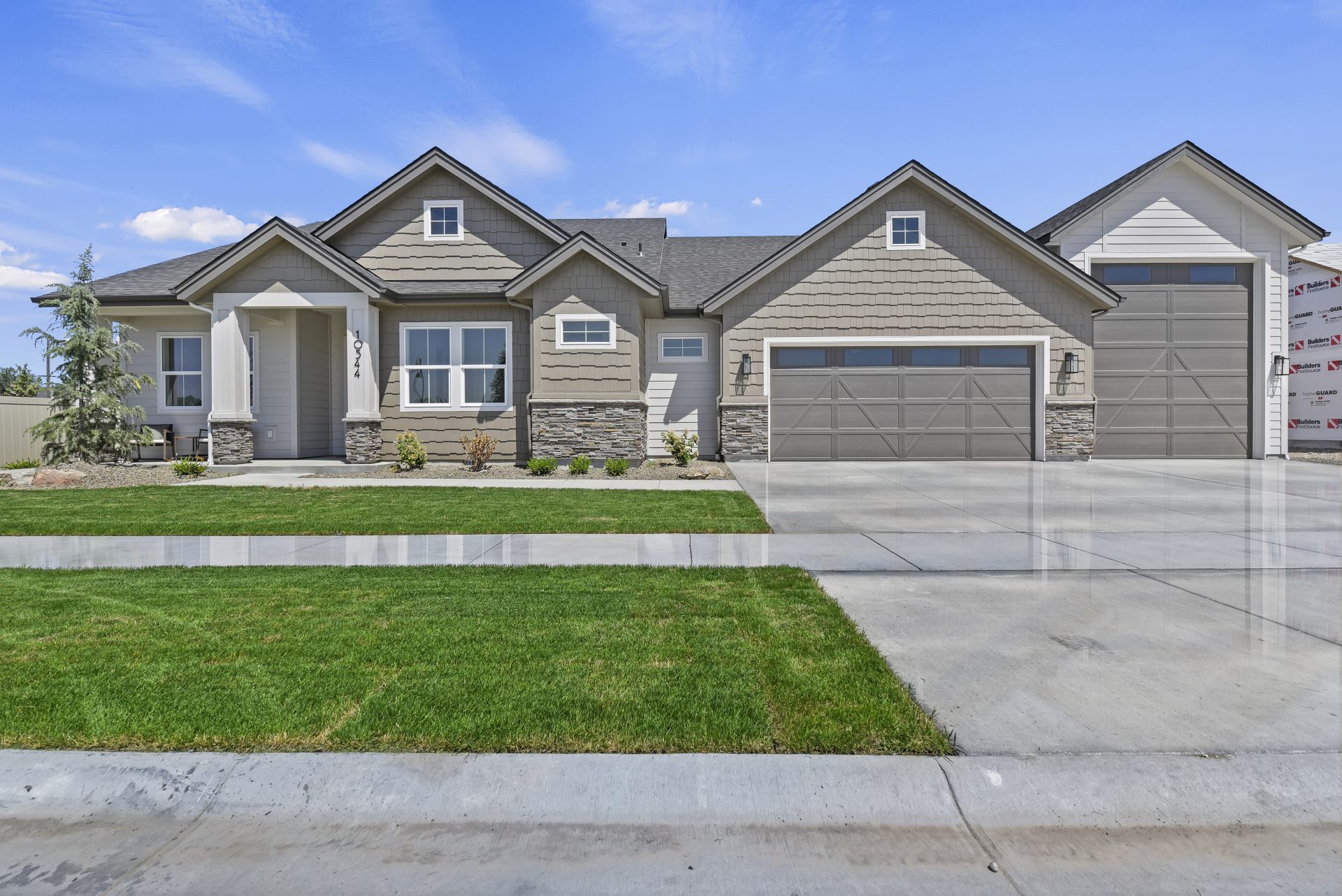 Front grass landscaped Craftsman style ranch home exterior elevation with 2-car garage and additional RV garage.