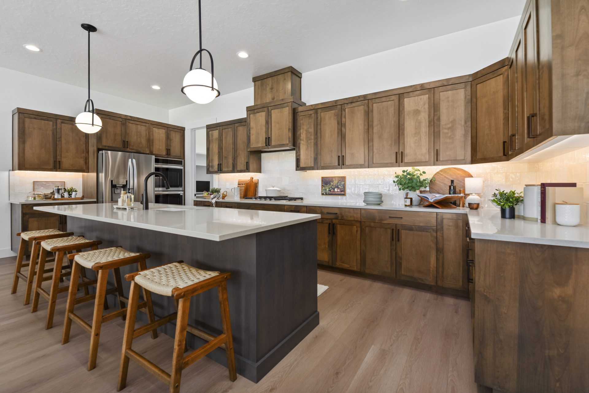 Chef's kitchen with 9 foot ceilings, canned lights, designer pendant lighting, dark beech wood cabinets, black fixtures, large island and white quartz countertops.
