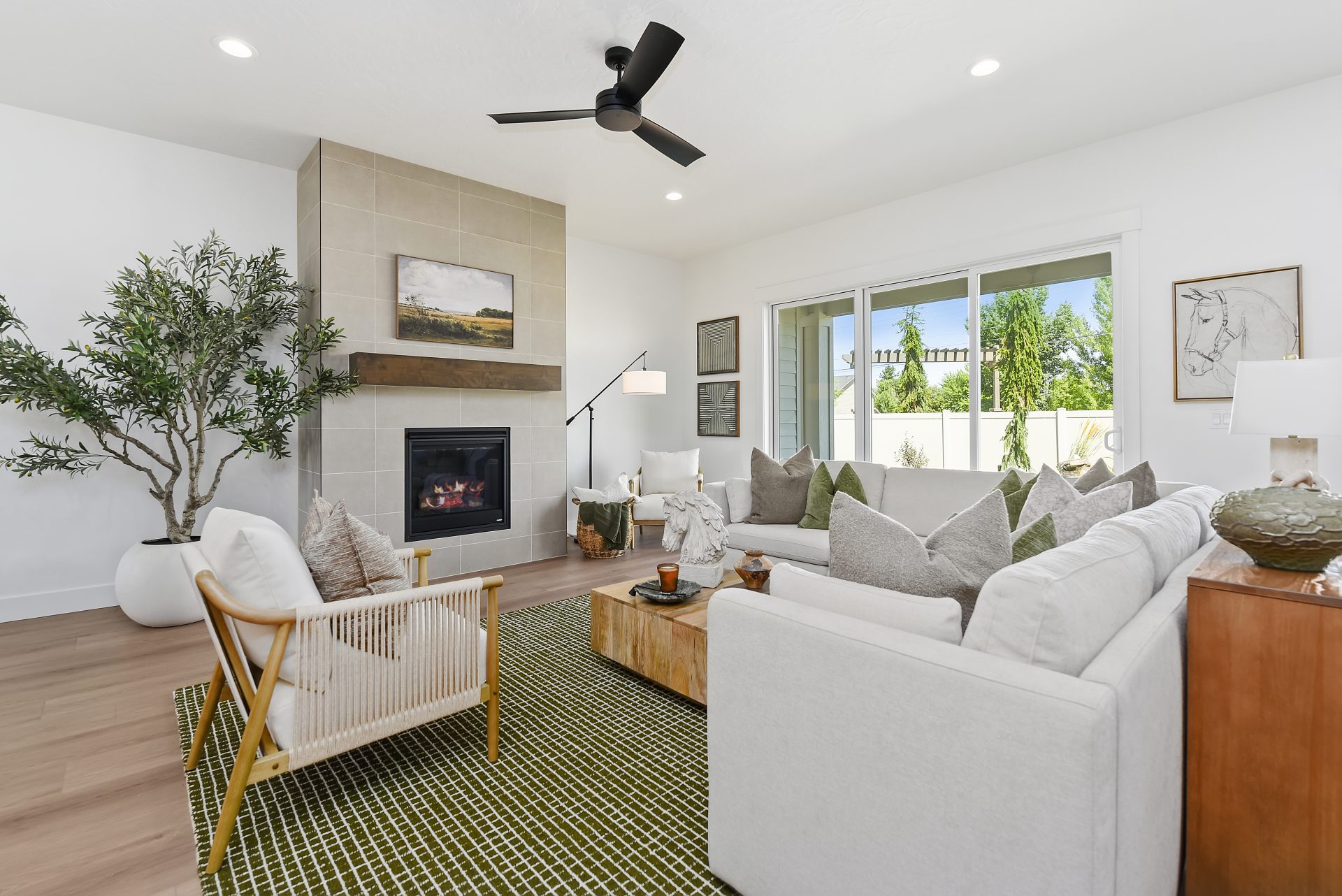 Living room with hardwood floors, electric fireplace, tiled, mantle, 9 foot ceilings, canned lighting and ceiling fan.