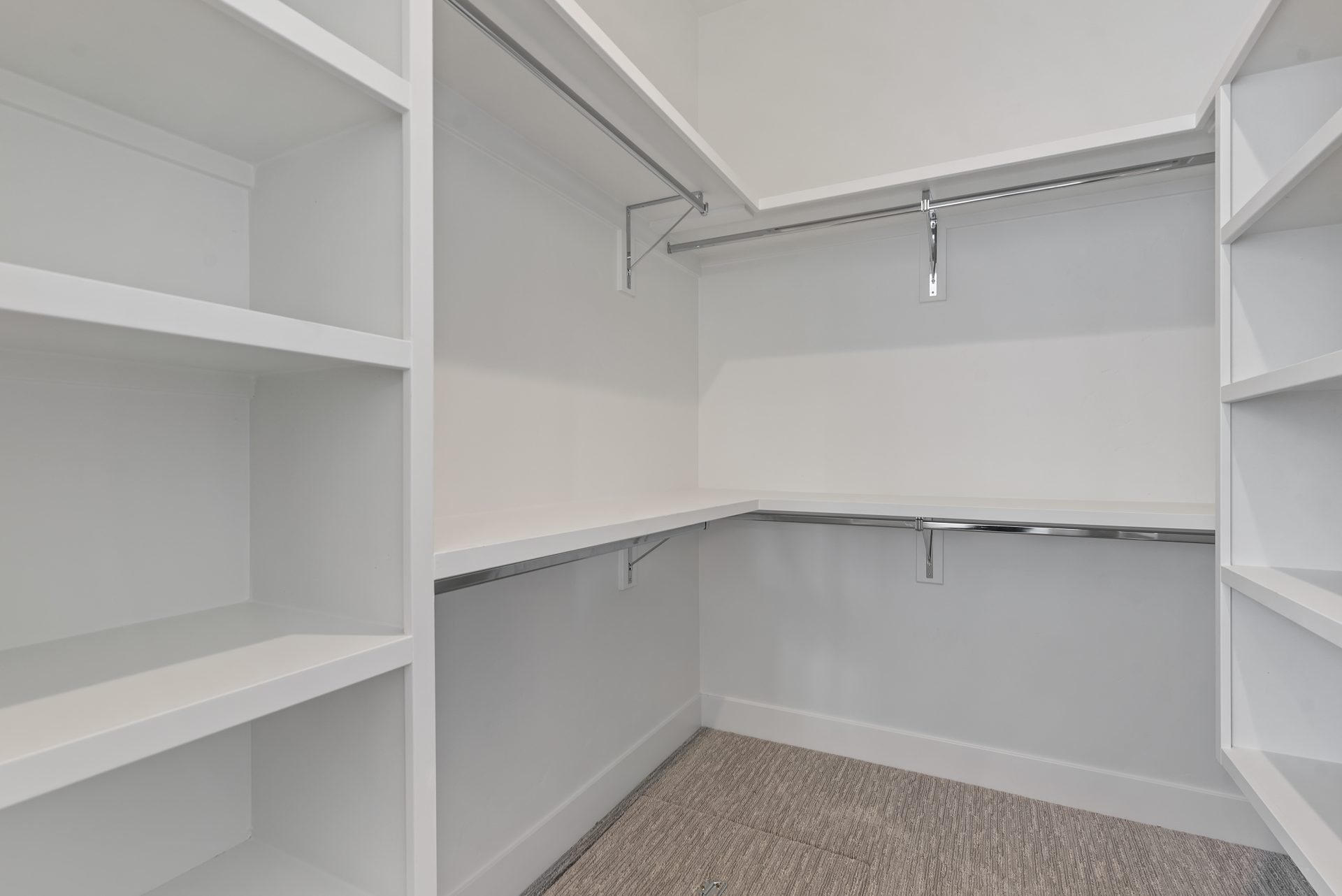 Closet with lots of shelving and two tiered metal hanging rods.