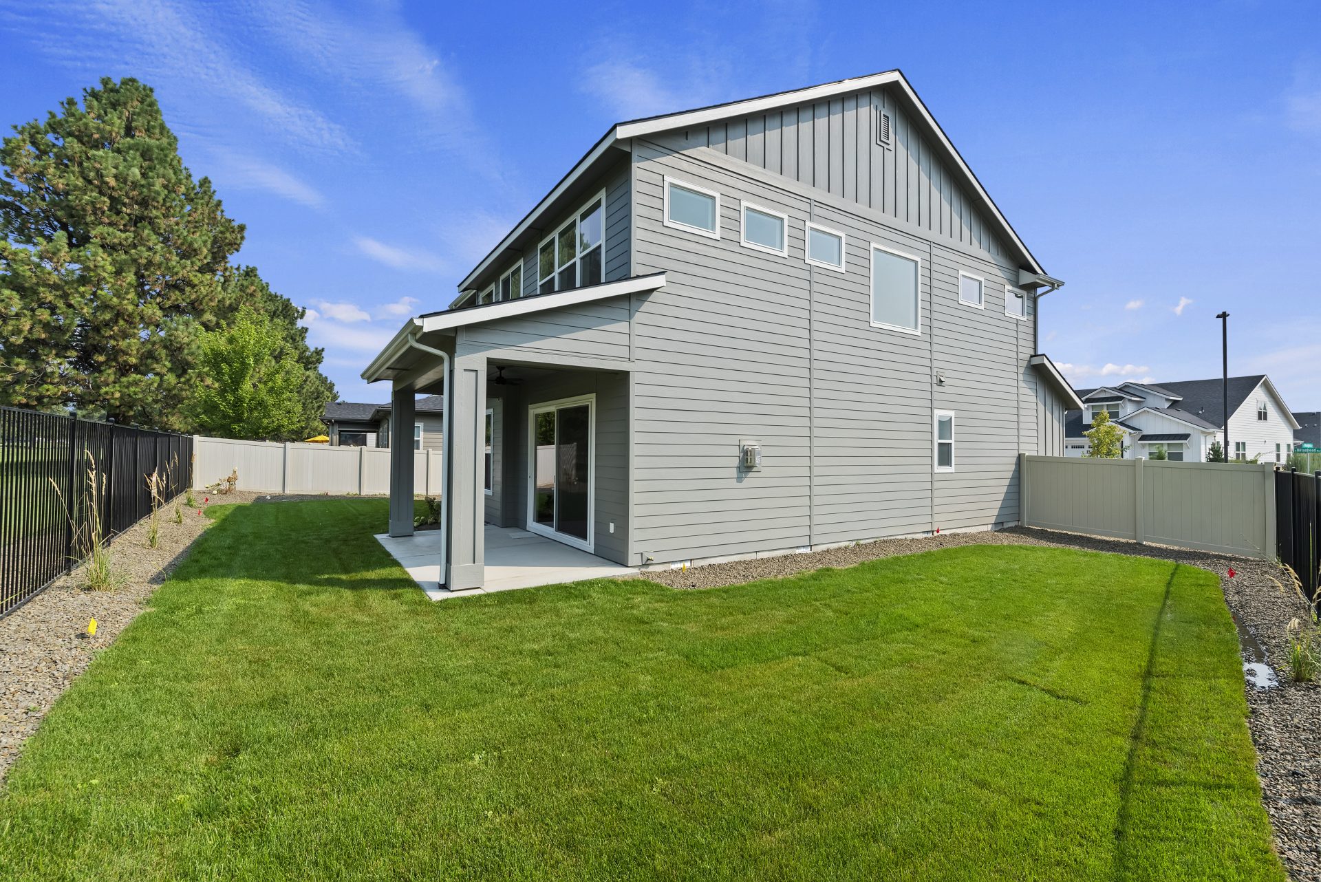 View of a backyard with green grass and a side view of a home with a covered porch.