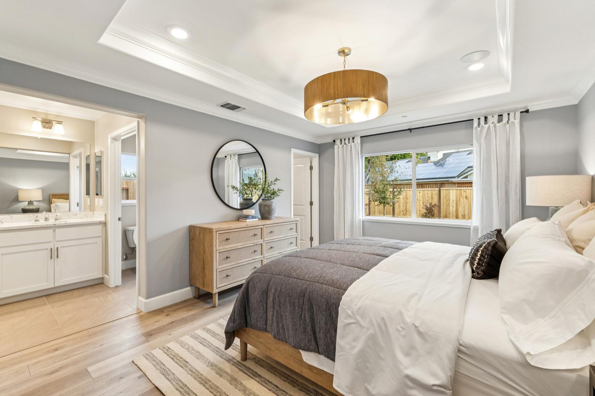 Primary suite with hardwood floors, large window, 9 foot ceilings with canned lighting and designer pendant over king bed, and 8 foot doorways to the primary bathroom and carpeted walk-in closet.