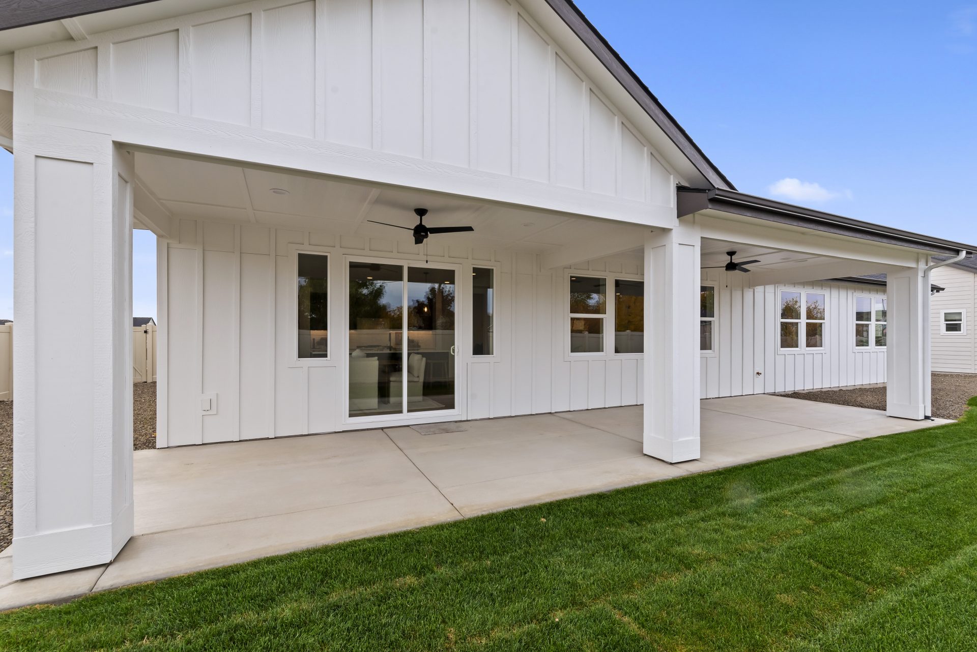 Exterior backyard with a porch, white color home with pillars and overhang over the porch area.