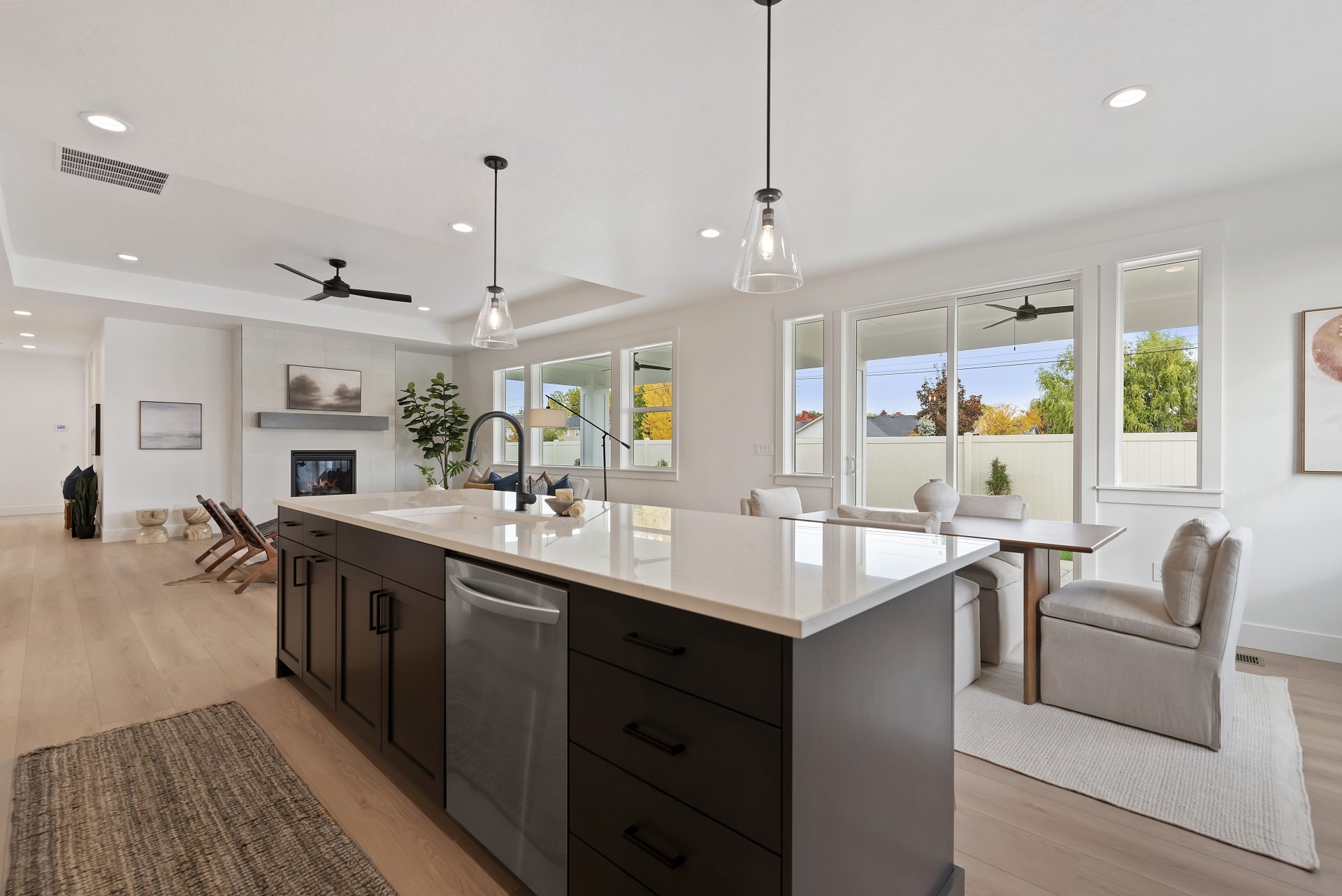 View from kitchen overlooking the island to the dining and living area, windows span the far wall creating a bright open space.