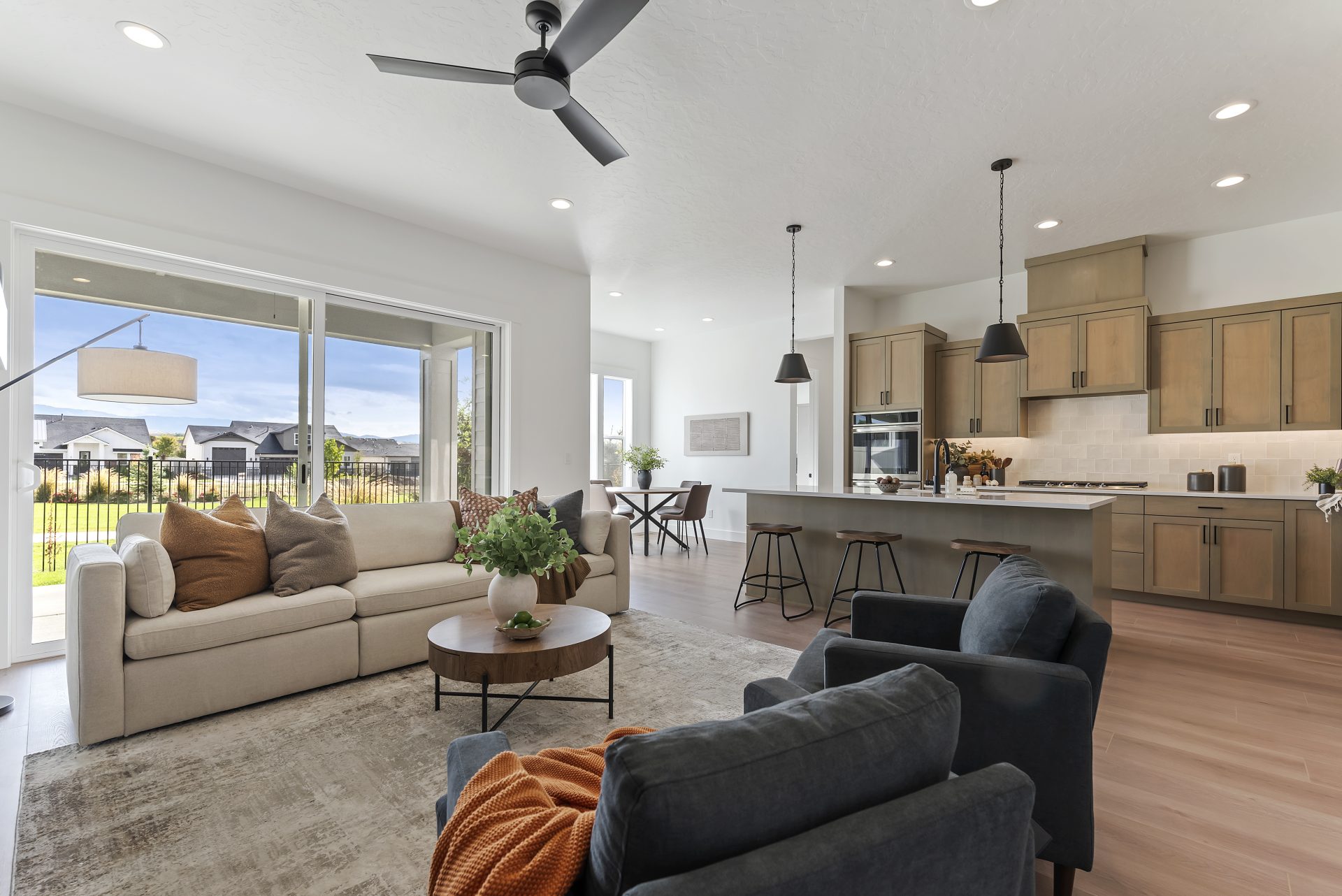View of the kitchen from the living room with a seating area, barstools at the kitchen island and a dining table in a nook.