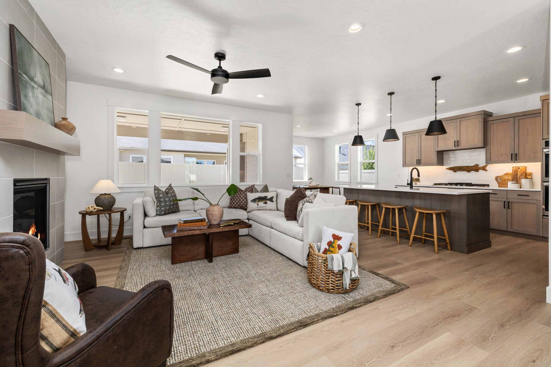 Two-story home entryway with a high ceiling and abundant natural light from upper-level windows. The space features light hardwood flooring, a wood console table with a round mirror and lamp, and a neutral runner rug. A carpeted staircase with a black met